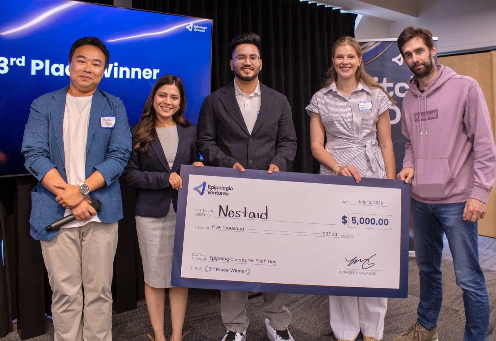 Nestaid accepting the 3rd place $5,000 check on stage at Epipelagic Ventures Pitch Day in Kendall Square